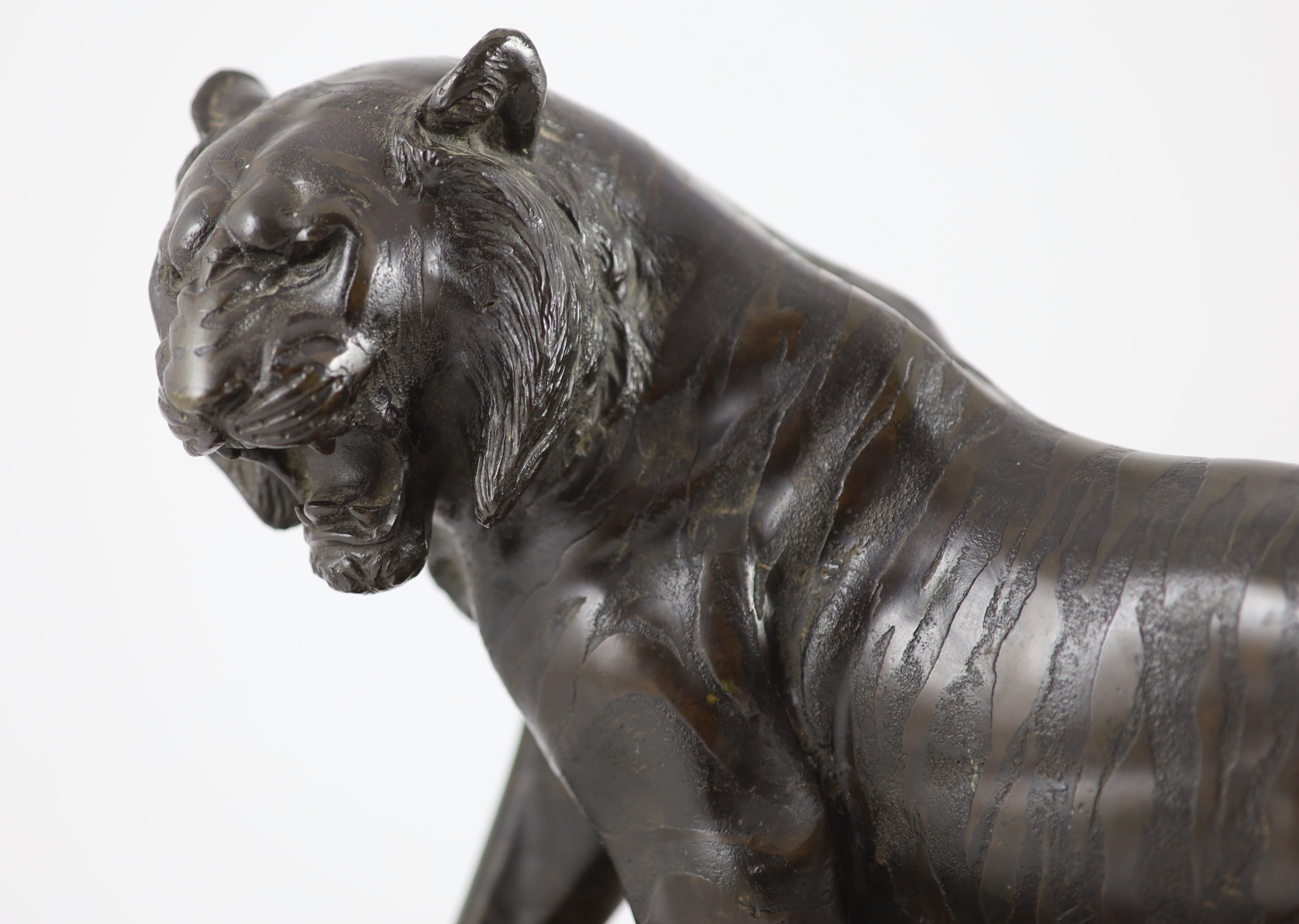 A large Japanese Meiji bronze model of a stalking tiger, Meiji period, 58.5 cm long, wood stand